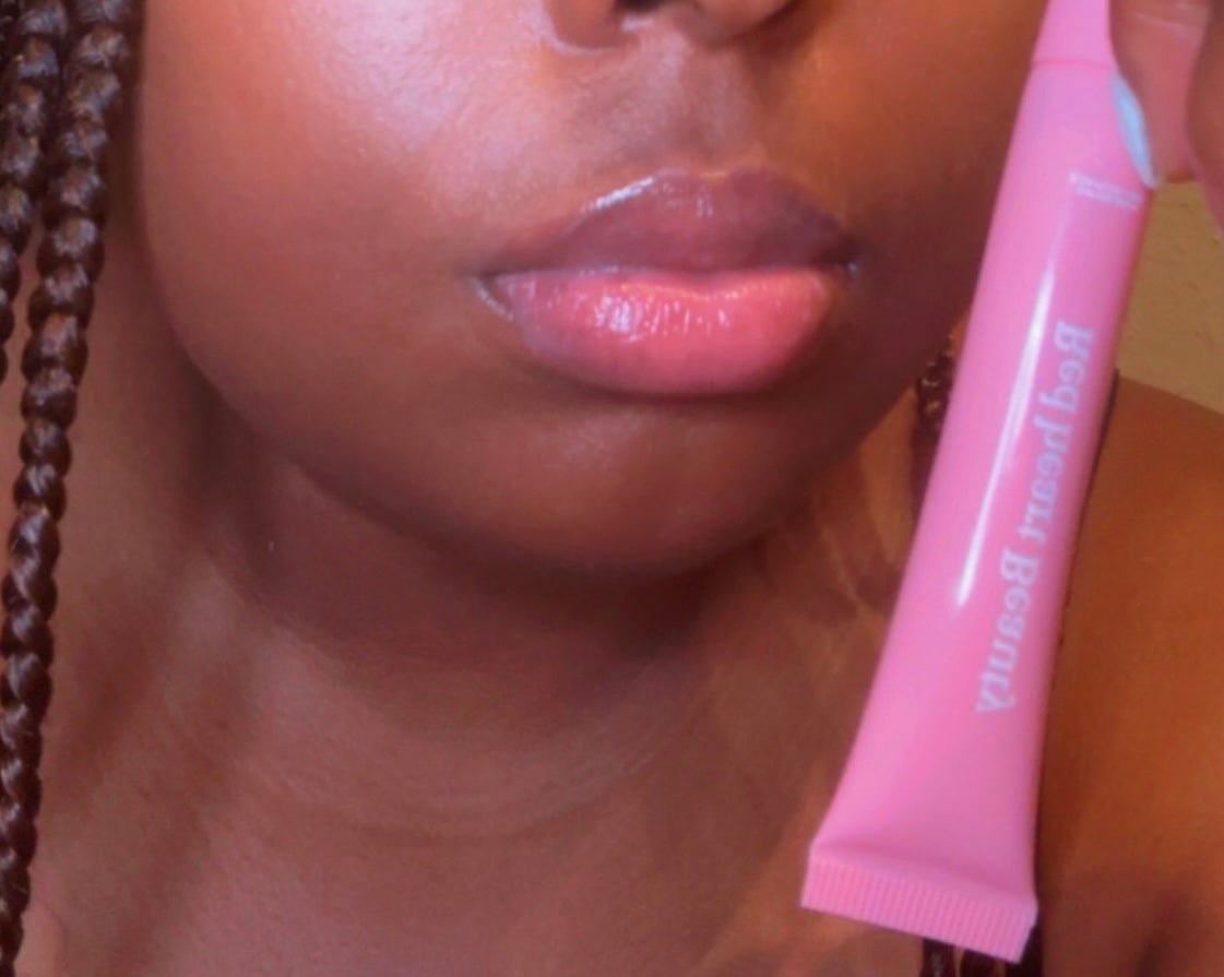 Close-up of a person applying pink lip balm with visible brand name.