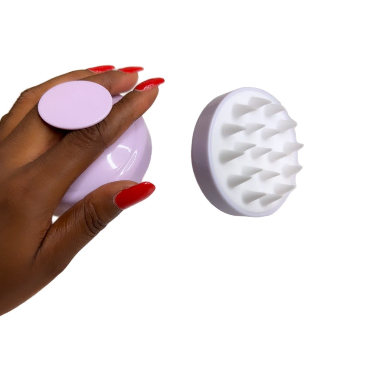 Hand holding a pink and white silicone scrubber on a light background