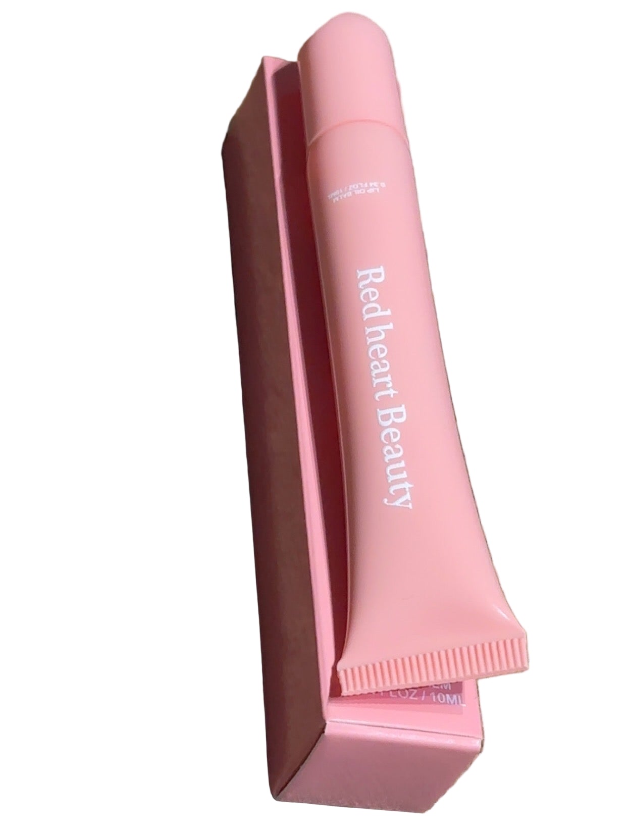 Pink lip balm with 'Red Heart Beauty' branding on a wooden surface