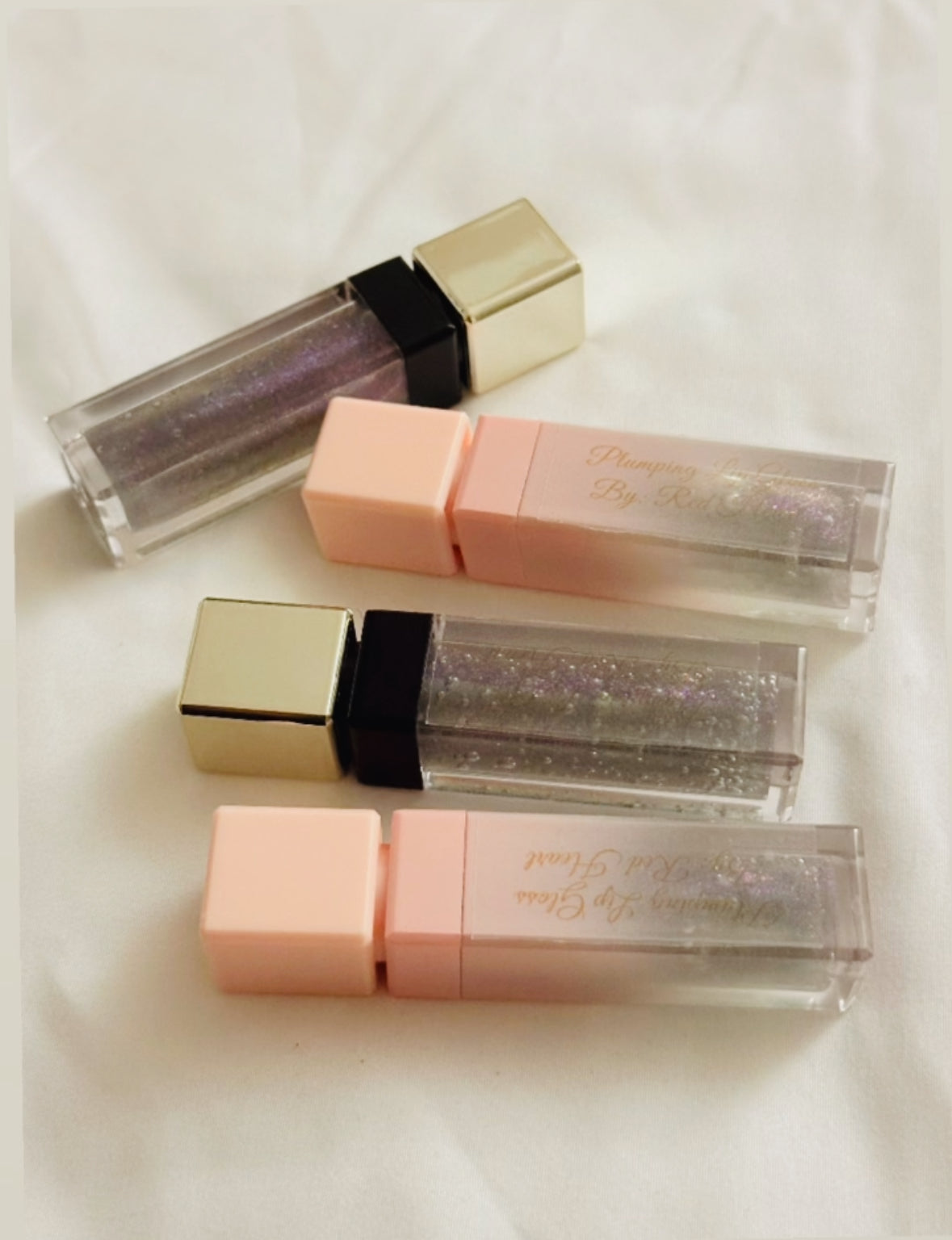 Set of lip glosses with glittery finish on a white background