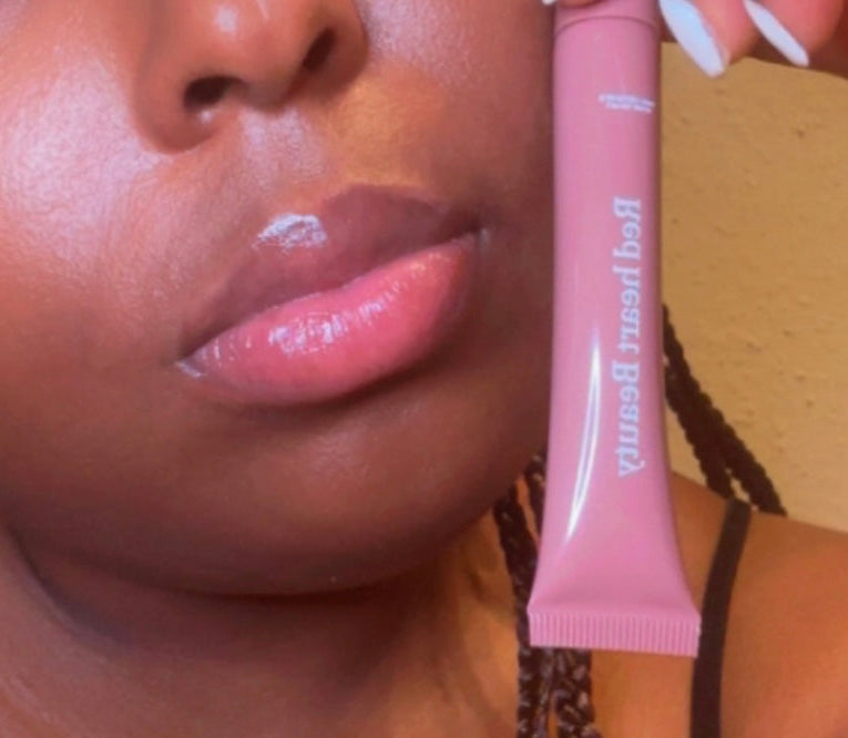 Close-up of a person applying pink lip gloss with a visible brand name.