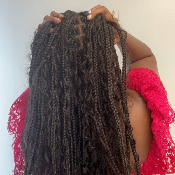 Person holding long braided hair with a plain background